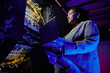 © Seventyfour - Low angle portrait of female network engineer setting up servers in data center lit by neon