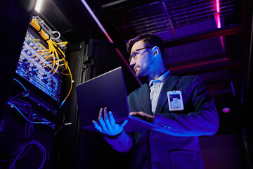 Low angle portrait of professional network engineer setting up servers in data center