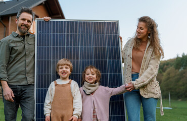 Happy family near their house with solar panels. Alternative energy source