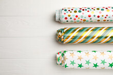 Different Colorful Wrapping Paper Rolls On White Wooden Table, Flat Lay. Space For Text
