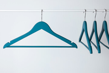 Wall Mural - Blue clothes hangers on metal rail against light background