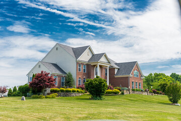 Country house in the suburbs of Leesburg, Virginia with a green lawn in the foreground. Blue sky, clear summer day.