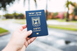 Human hand holding a blue State of Israel Israeli passport travel document outdoors