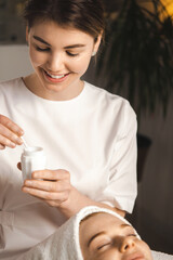 Wall Mural - beautician applying cream on the patient's face satisfied with the services of the beauty salon. lig