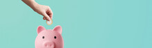 Man Depositing Coins In A Pink Piggy Bank On A Blue Background - Savings Concept