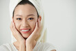© DragonImages - Face of young Vietnamese woman touching her glowy skin after morning beauty routine
