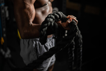 Muscular african american man posing with rope in gym. 