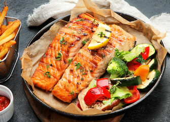 Canvas Print - Salmon steak with vegetables on dark background.