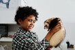 © pressmaster - Portrait of joyful African American boy standing in exma room in vet clinic holding his ferret looking at it