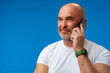 Portrait of an adult man talking on the phone against blue background.