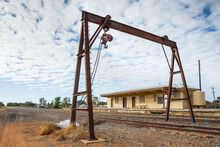 A Rusting Metal Winch Framework Over Railway Tracks At A Small Outback Railway Station