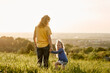 © gpointstudio - Little girl standing with mom at the meadow and turning to camera side