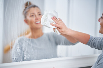 Wall Mural - Picture of yound woman cleaning mirror window