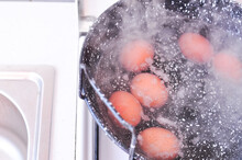 Eggs In Shell In Boiling Water In Black Pot On The Stove . High Quality Photo