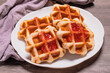 © mangolovemom - Four waffles in a white plate.and gray background.