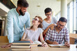 © NDABCREATIVITY - Happy university students studying with books in library. Group of multiracial people in college