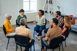 © bnenin - Top view of a group of people, sitting in a circle, talking about their mental health.