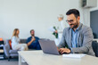 © bnenin - Businessman working over the laptop while his colleagues taking a break in the background.
