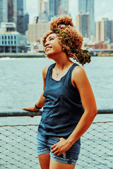 Portrait beautiful young adult woman afro hairstyle with Manhattan New York City skyline in the background outdoors shot