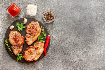 Wall Mural - grilled pork steaks with spices on stone background with copy space for your text