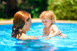 A woman teaches a baby to float on the water and swim. Summer outdoor fun in the pool in the villa. Happy child is having fun. Family happiness. Mom and daughter in the pool