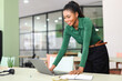 © Vadim Pastuh - Wholly directed on task young african-american female employee stands near desk and using modern laptop at workplace. Focused successful black woman looking at laptop screen