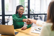 Business women shaking hands in the office during business meeting. Two diverse female entrepreneurs on meeting in boardroom. Female recruiter and employee confirm hiring
