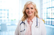 © gzorgz - Smiling senior female doctor portrait while standing at the hospital foyer