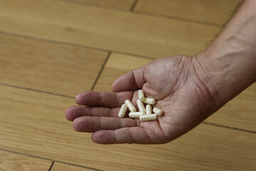 Men hand holding a white medicine. Hand hold white pills in the room. Close up.