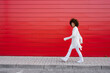 © VISTA by Westend61 - Smiling woman walking on sidewalk by red wall
