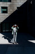 © VISTA by Westend61 - Young businesswoman wearing VR goggles in front of office building