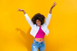 © VISTA by Westend61 - Smiling woman with hands raised in front of yellow wall