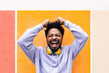 Excited Man With Arms Raised Screaming In Front Of Orange Wall