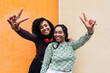 © VISTA by Westend61 - Happy friends gesturing peace sign in front of wall