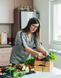 © Tijana - Beautiful Woman Taking Fresh Vegetables from a Wooden Crate at Kitchen Desk and Making Vegetarian Lunch at Home