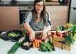 © Tijana - Serious Woman in Apron Preparing Salad at the Kitchen Desk Full With Fresh Vegetables