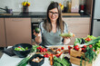 © Tijana - Happy Woman Holding Avocado And Zucchini While Sitting At Kitchen Desk