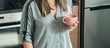 © Tijana - An anonymous businesswoman drinking coffee while standing in the kitchen