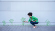 © VISTA by Westend61 - Crouching woman plucking painted flower from wall