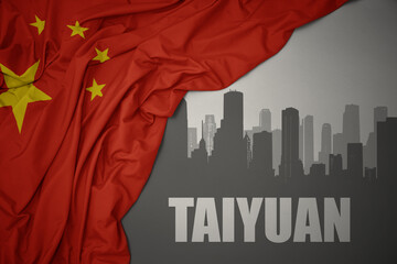 abstract silhouette of the city with text Taiyuan near waving national flag of china on a gray background.