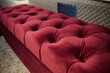 Focus on a red velour ottoman or footstool dispayed for sale in a furniture store