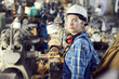 © Mediaphotos - Portrait of serious tomboy in hardhat and protective goggles working with lathe at factory