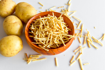 straw potato chips in a bowl on white background.