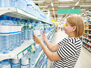 Wall Mural - Woman with bottles of water in store