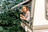 Fototapeta Miasto - A young woman looks out of the trailer window at summer time