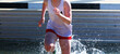 High school girls is very wet exiting the water of the steeplechase during a track race