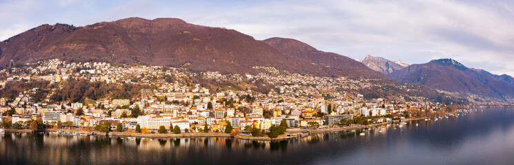 View from drone of lake Maggiore and houses of swiss city Locarno in cloudy winter day