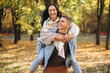 © anatoliycherkas - Happy couple, man holding a woman behind his back and having fun together in the autumn park