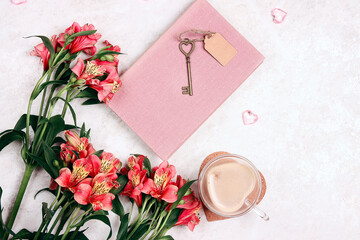 Alstroemeria flowers, a cup of coffee and a book on a light marble table.