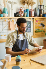 Aufkleber - Serious guy in casualwear and apron looking at screen of digital tablet while scrolling through online information and creative ideas